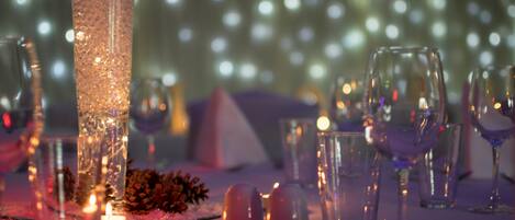 Una mesa dispuesta con vajilla transparente, velas y piñas, evocando un ambiente festivo o elegante para cenar.