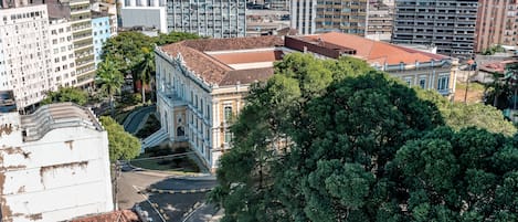 A cityscape with a mix of modern and historic buildings, a prominent tree, and a curved road.
