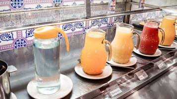 A beverage station with various drinks in pitchers and glasses, labeled with names like "Maracuja" and "Cai."