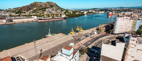 Um rio com uma ponte, edifícios e uma colina ao fundo.