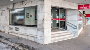 Entrada de hotel con fachada de mármol, puertas de vidrio y una escalera que conduce al interior.