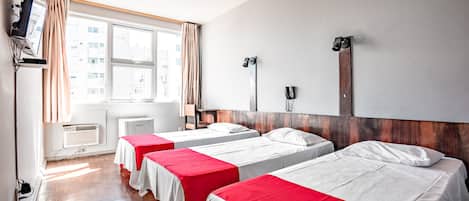 Ein Hotelzimmer mit zwei Betten, einem Fernseher, einem Schreibtisch und einem fensterbepflanzten Fenster.
