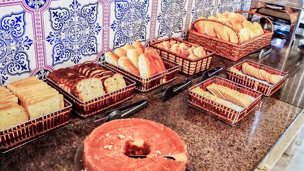 Una exhibición de panadería variada, incluyendo pan, galletas y un pastel, sobre una encimera con un salpicadero de baldosas estampadas.
