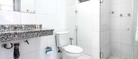 A bathroom with a white toilet, a shower, and a granite countertop.