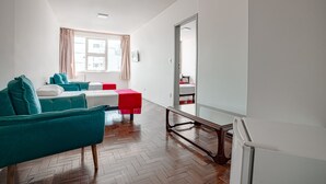 Una sala de estar moderna con un sofá azul aguamarina, un reposapiés rojo y un espejo grande.
