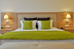 Una habitación de hotel con una cama grande, dos lámparas de noche y un cabecero de madera.