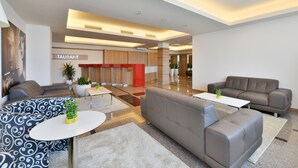 A modern lobby with a restaurant sign, leather sofas, a coffee table, and potted plants. - Suite Hotel Sofia (Sofia)