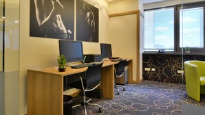A modern office space with two desks, computers, and chairs. There are abstract wall art pieces and a patterned carpet. - Suite Hotel Sofia (Sofia)