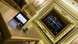 A luxurious hotel lobby with ornate wall decorations, a digital display, and a framed mirror. - Cassiel Hotel (Ankara)