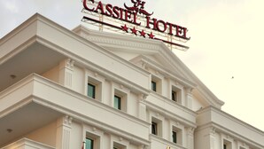 A large, white building with the sign "Cassiel Hotel" at the top. There are two flags on flagpoles in front of the building. - Cassiel Hotel (Ankara)