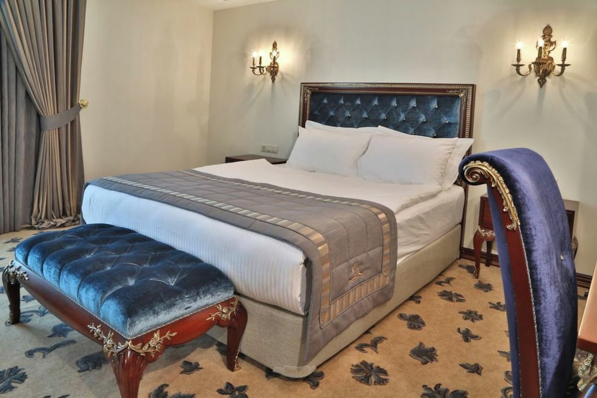 A neatly made bed with a tufted headboard, a matching footboard, and a bedside table with a lamp.