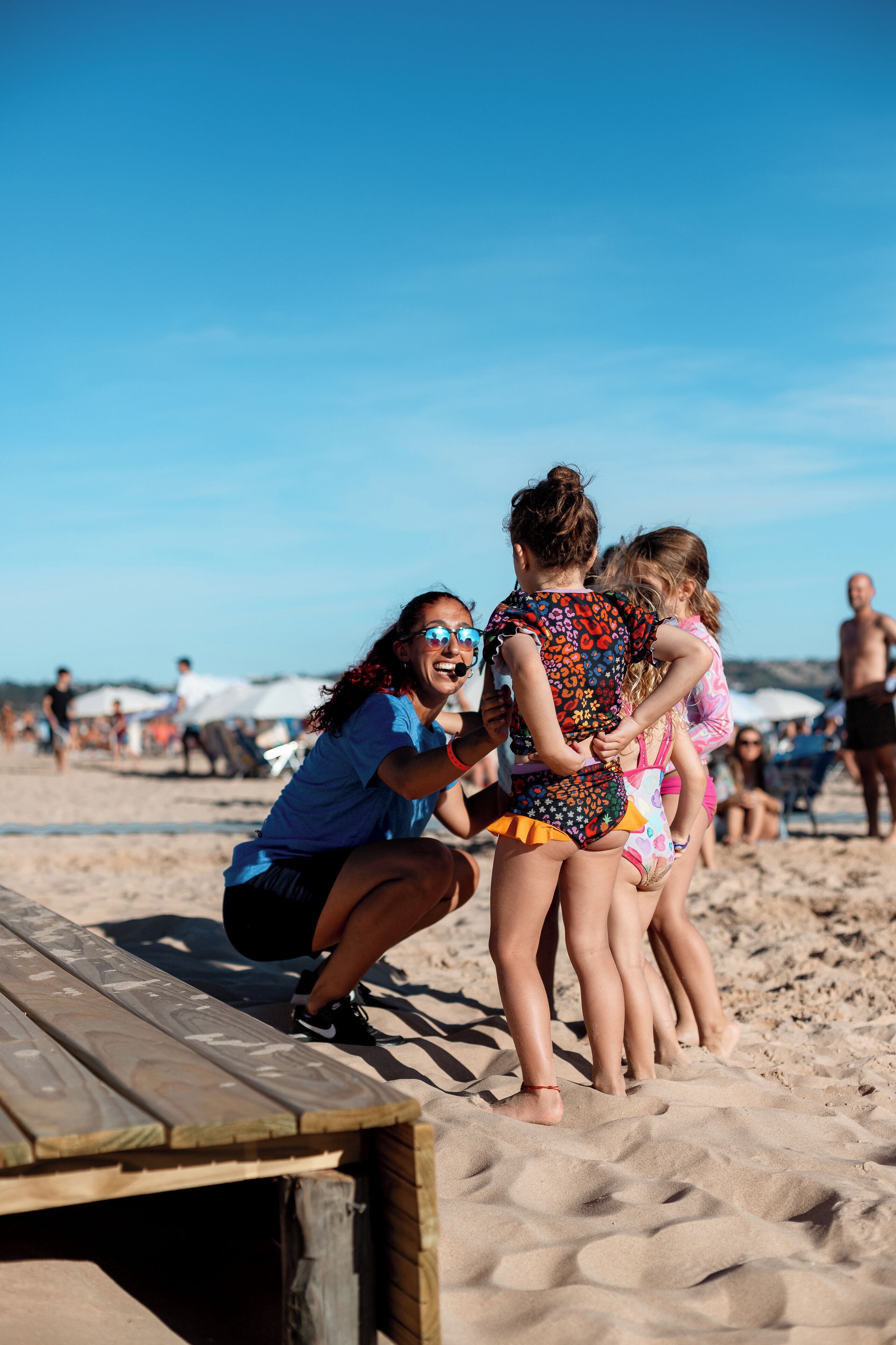 A wooden deck on a sandy beach with people in swimwear.