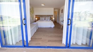 Un dormitorio con cama, mesitas de noche y vistas a través de un ventanal.