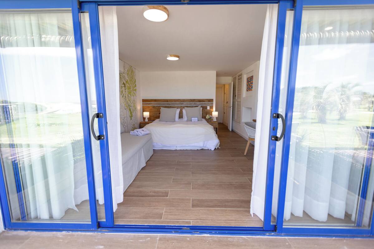A bedroom with a bed, bedside tables, and a view through a glass door.