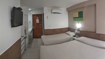 Habitación de hotel con dos camas, televisión, aire acondicionado y una mesita de noche con lámpara.