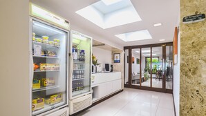 A reception area with a glass-fronted refrigerator stocked with food items, a reception desk, and a sign indicating directions to the restaurant and garage.