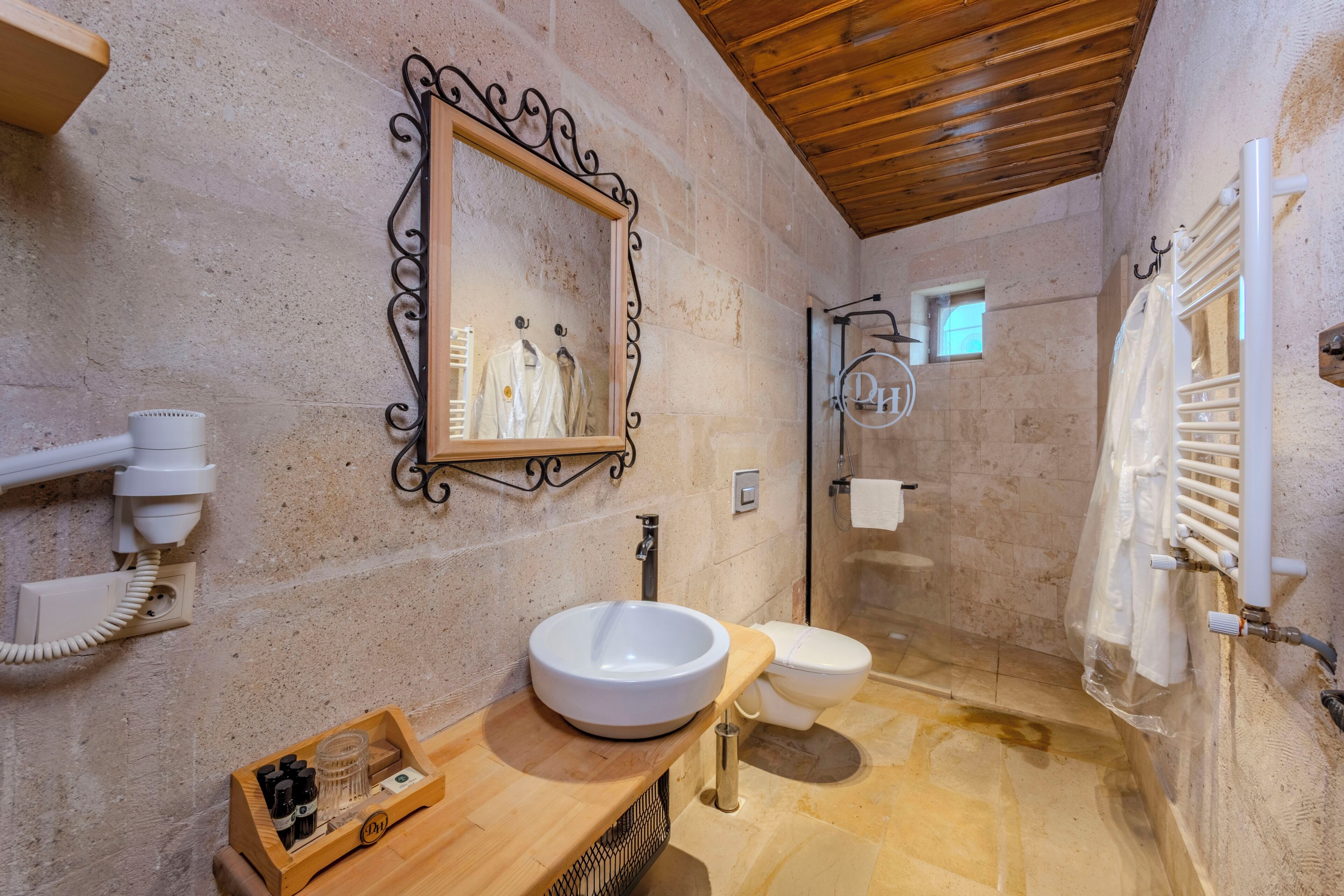 A bathroom with a wooden vanity, a sink, a toilet, and a shower area.