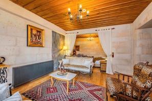 A cozy living room with a wooden ceiling, a patterned rug, a sofa, a leopard print chair, and a painting on the wall. - Duven Hotel Cappadocia  (Nevsehir)