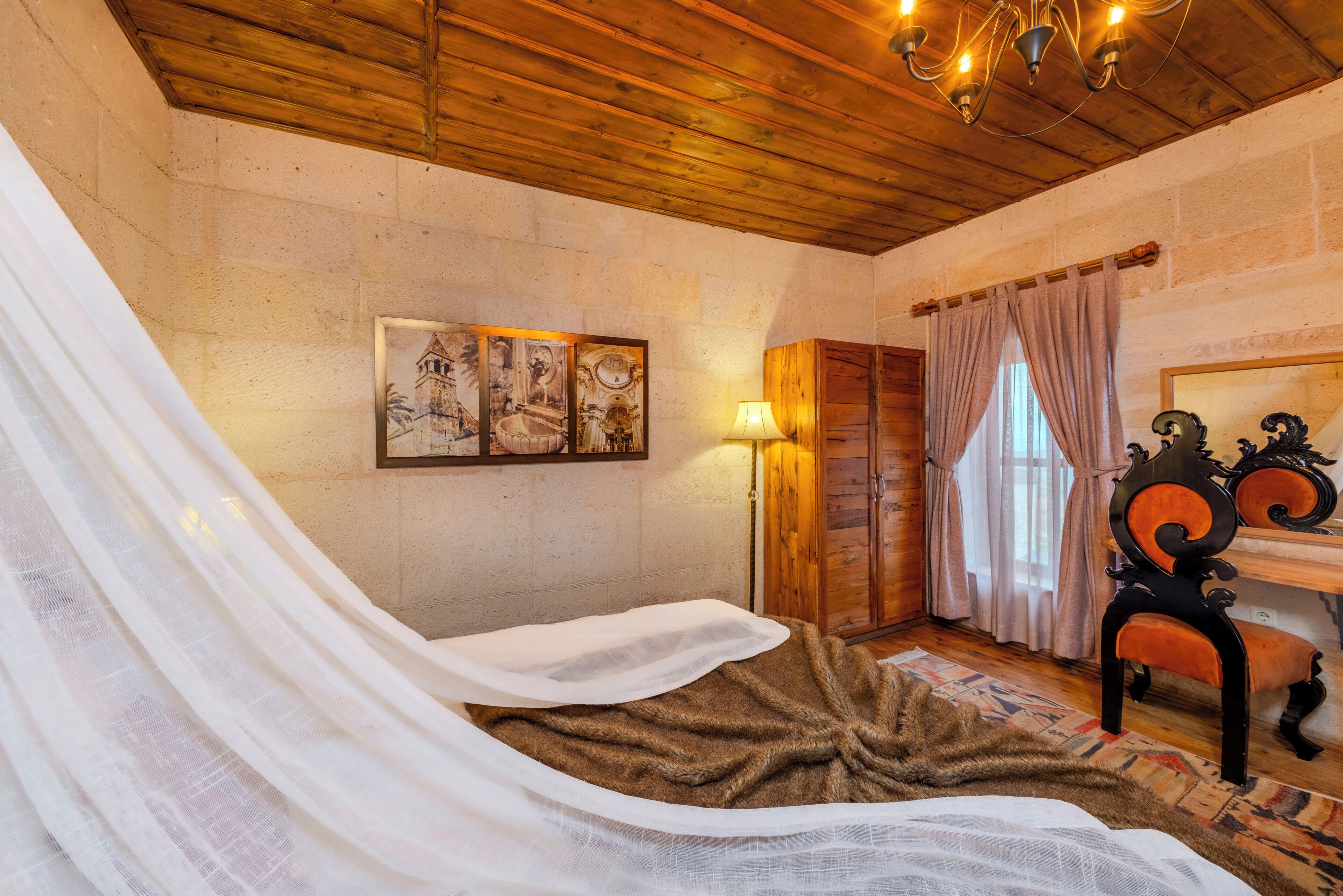 Quarto com uma cama, um guarda-roupa de madeira, uma luminária e um quadro na parede.