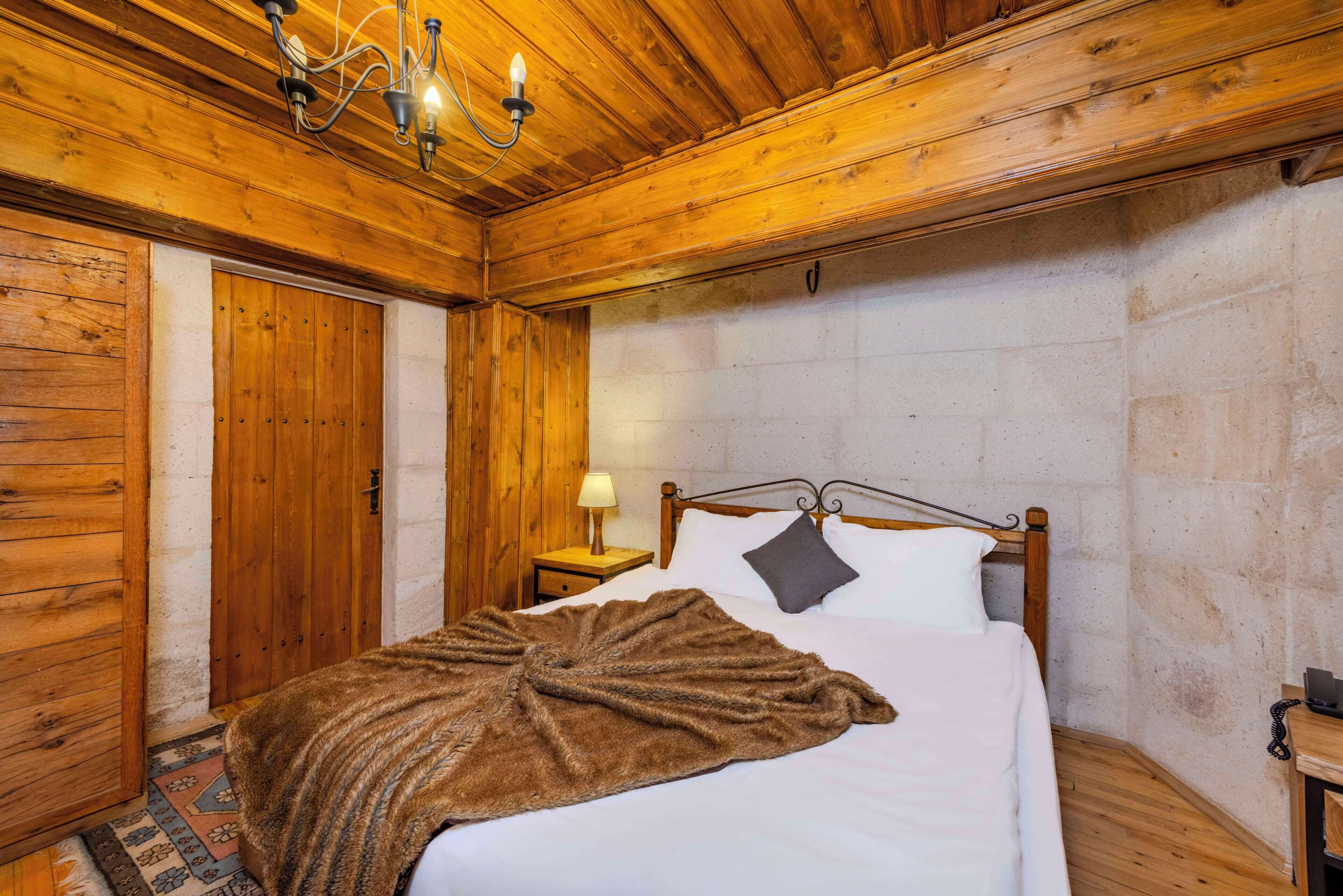 A wooden-paneled room with a bed, a nightstand, a lamp, and a telephone.