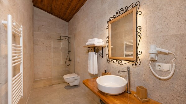 A bathroom with a shower, toilet, sink, and a mirror with a decorative frame.