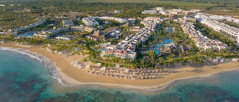 Vista aérea de un resort con varias construcciones, una playa y aguas turquesas cristalinas.