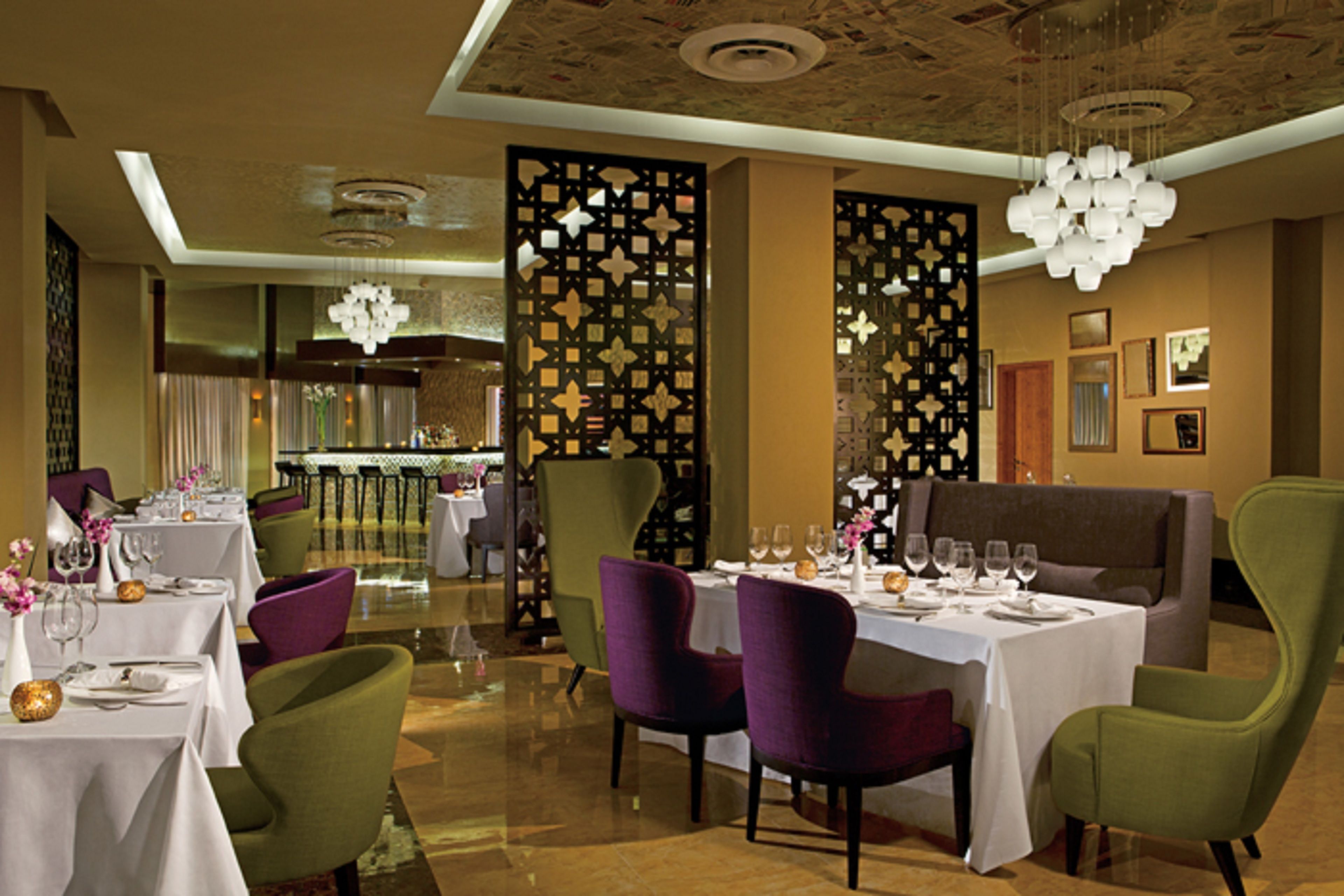 Un espace repas avec des tables dressées pour le repas, des chaises et un élément de séparation décoratif.