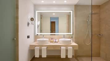 A modern bathroom with two sinks, a large mirror, and a glass-enclosed shower.