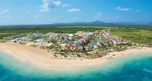 Een resort met meerdere gebouwen, een strand en helderblauw water.