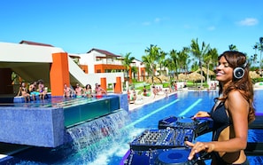 A pool area with a DJ booth, palm trees, and a modern building with orange and white colors. - Breathless Punta Cana Resort & Spa - Adults Only - All Inclusive (Punta Cana)