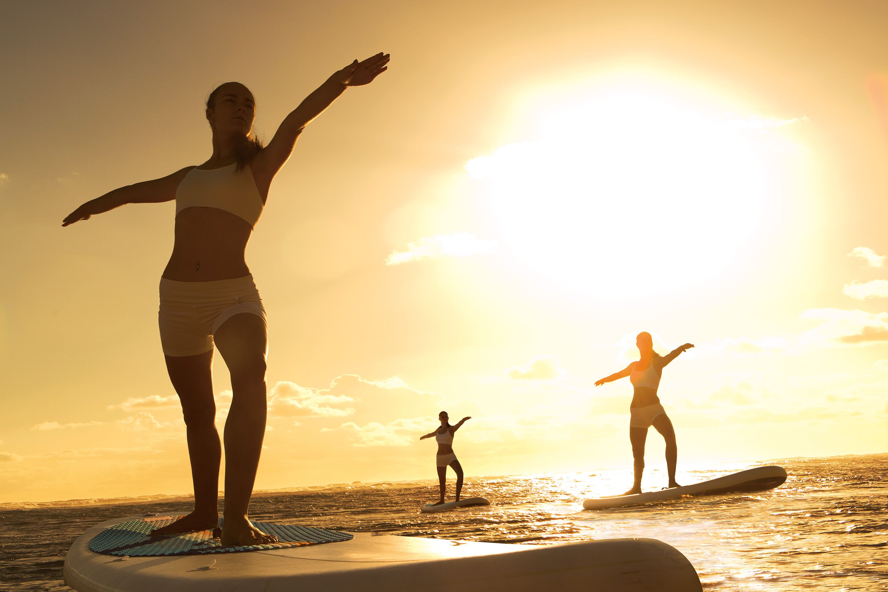 A person standing on a surfboard in the ocean during sunset.
