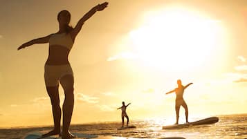 A person standing on a surfboard in the ocean during sunset.