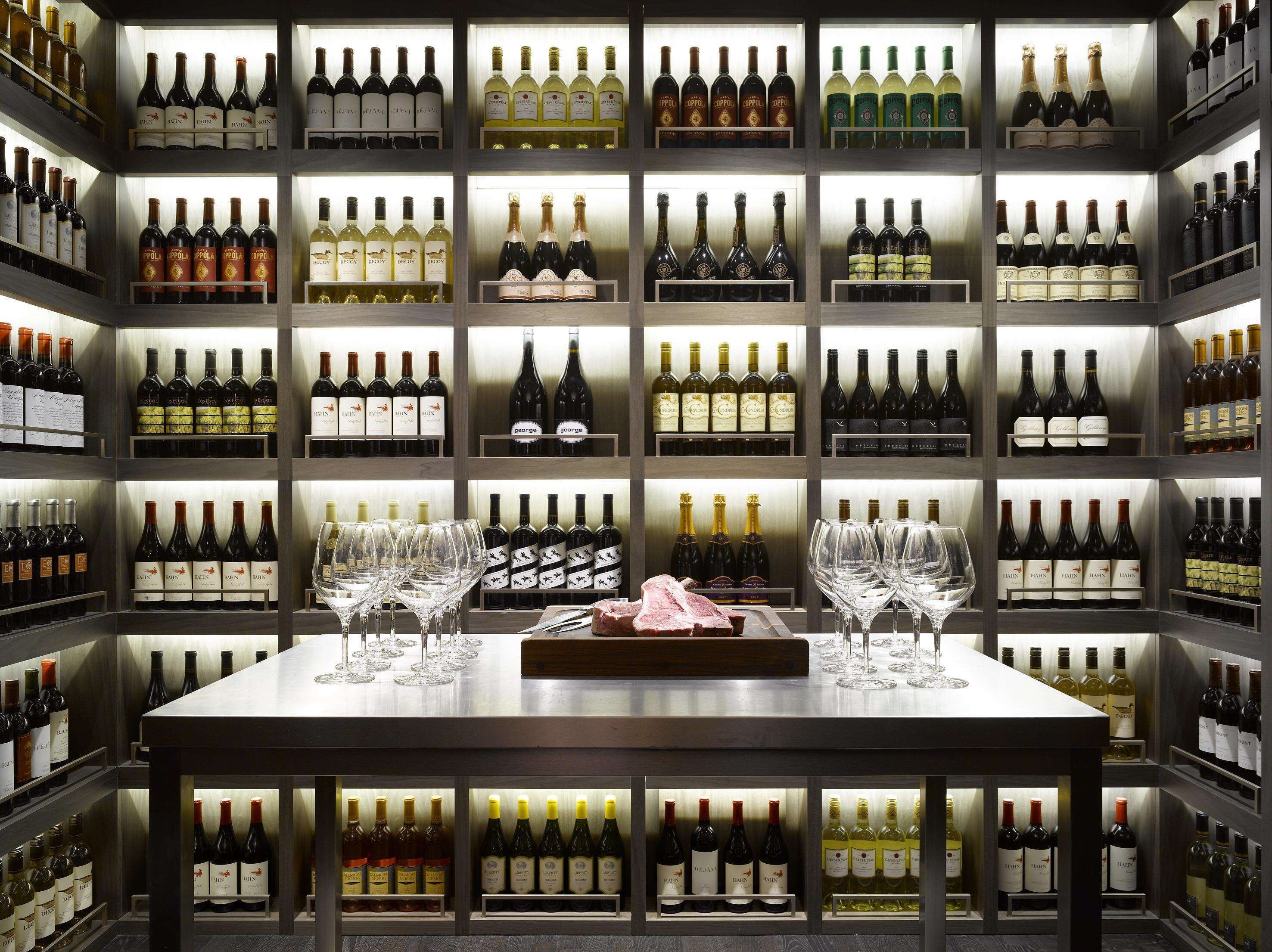 A wine cellar with multiple shelves of wine bottles and glasses.