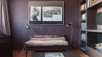 A modern room with a dark leather sofa, a coffee table with a magazine, a bookshelf, and a framed photograph on the wall.