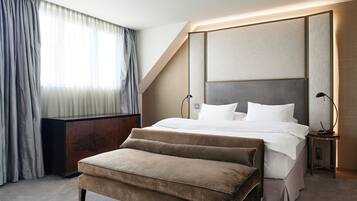 A modern hotel room with a large bed, a bedside table, a lamp, and a bench.