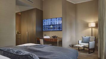 Et hotelværelse med seng, skrivebord, stol, fjernsyn og lampe.