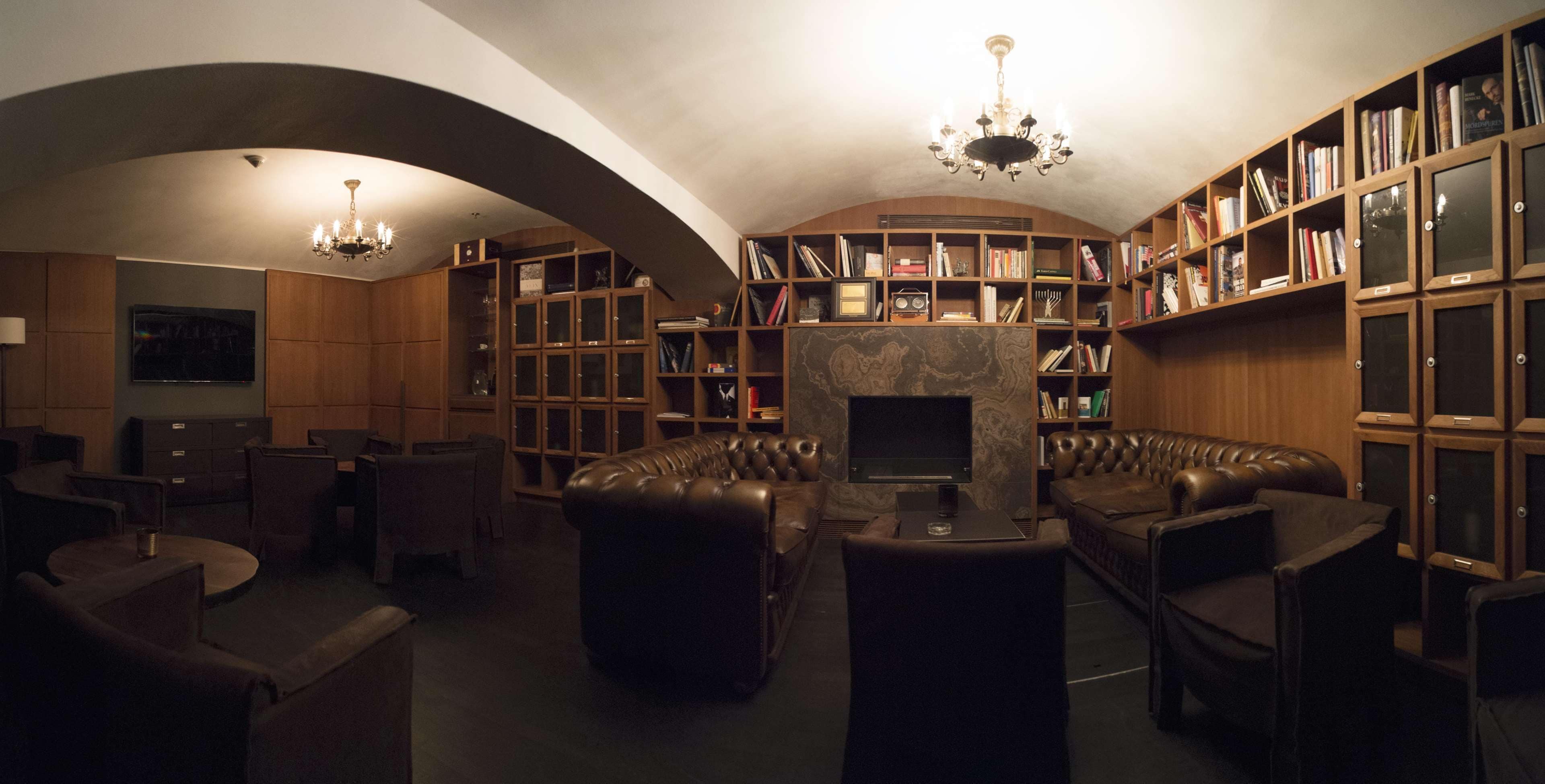 A library with leather sofas, bookshelves, and a fireplace.