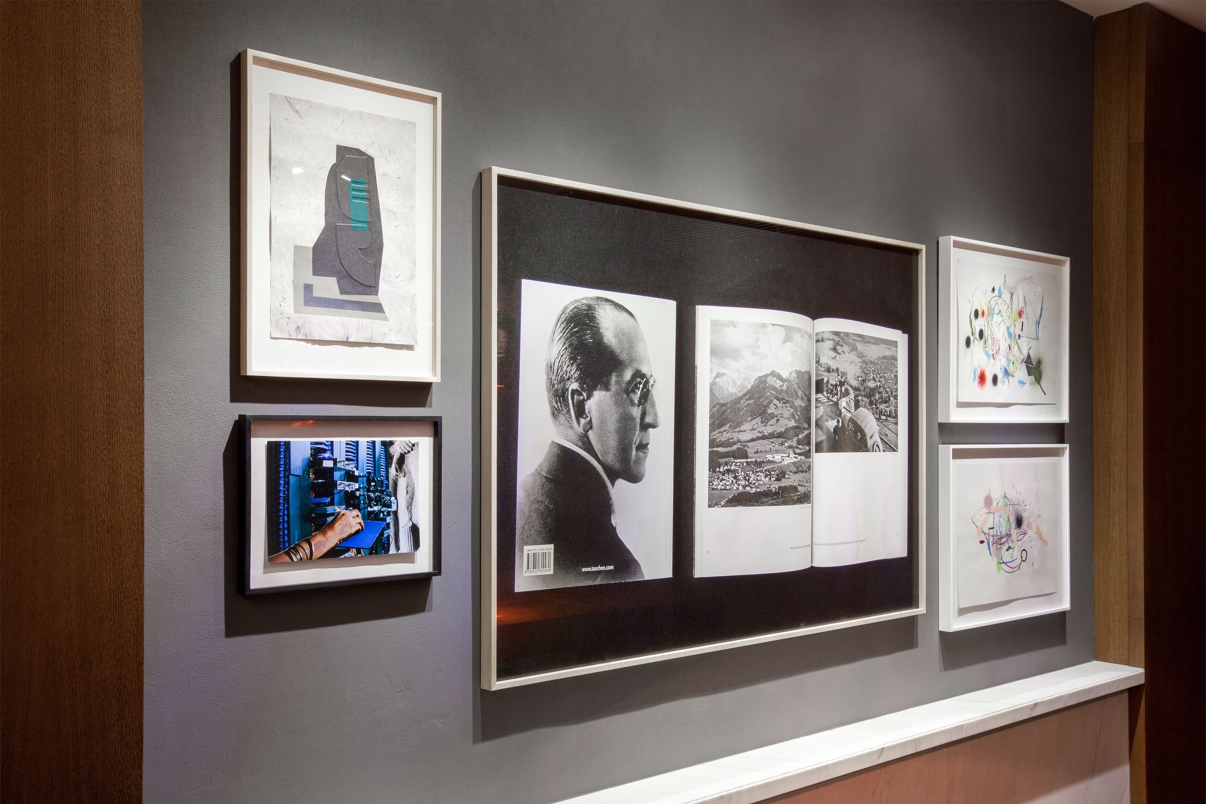 A wall with framed artwork, including a portrait, a landscape, and abstract art.