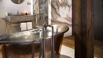 A modern bathroom with a freestanding bathtub, a round mirror, and a vanity with a marble countertop.