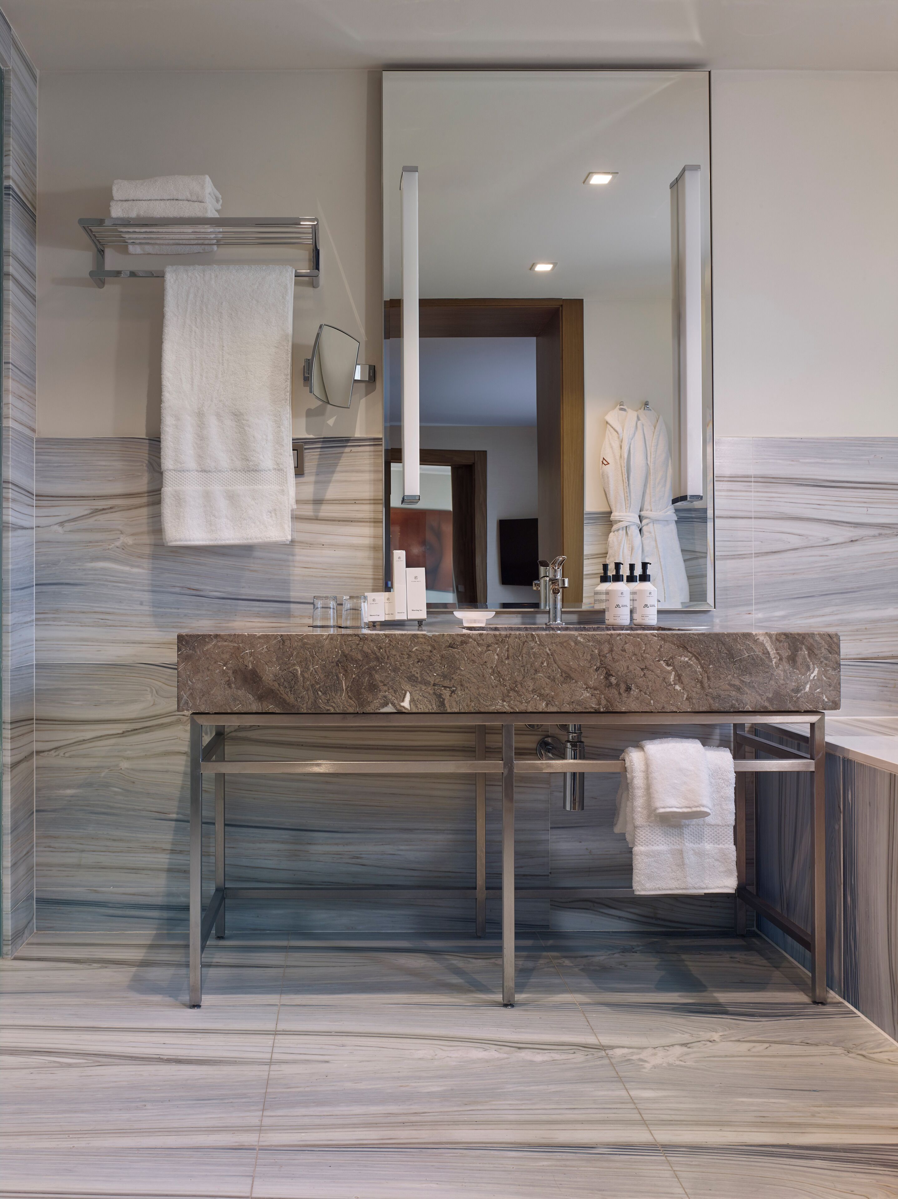 Une salle de bain moderne avec un comptoir en marbre, un grand miroir et un porte-serviettes.