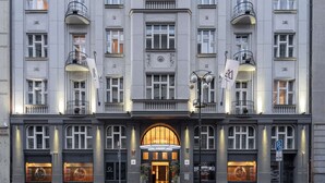 A large, multi-story hotel with a symmetrical facade, multiple balconies, and a central entrance with a large arched doorway. - The Emblem Prague Hotel  (Prague)
