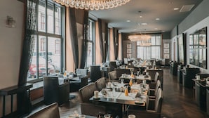 A spacious restaurant with multiple dining areas, large windows, and elegant chandeliers. - The Emblem Prague Hotel  (Prague)