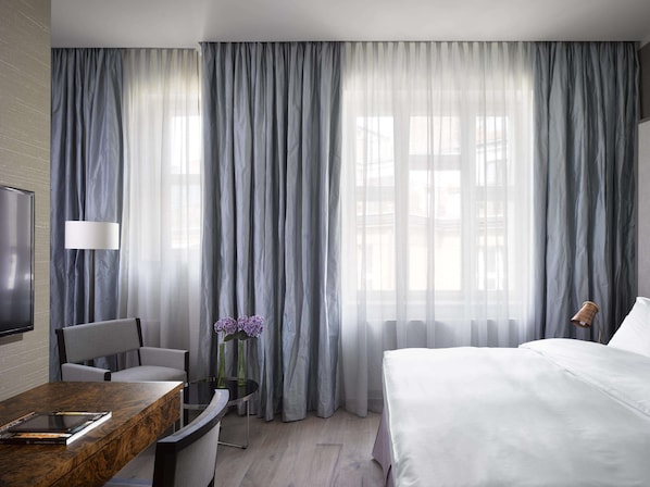 Une chambre d’hôtel avec un lit, un bureau avec une chaise, une lampe et un vase avec des fleurs.