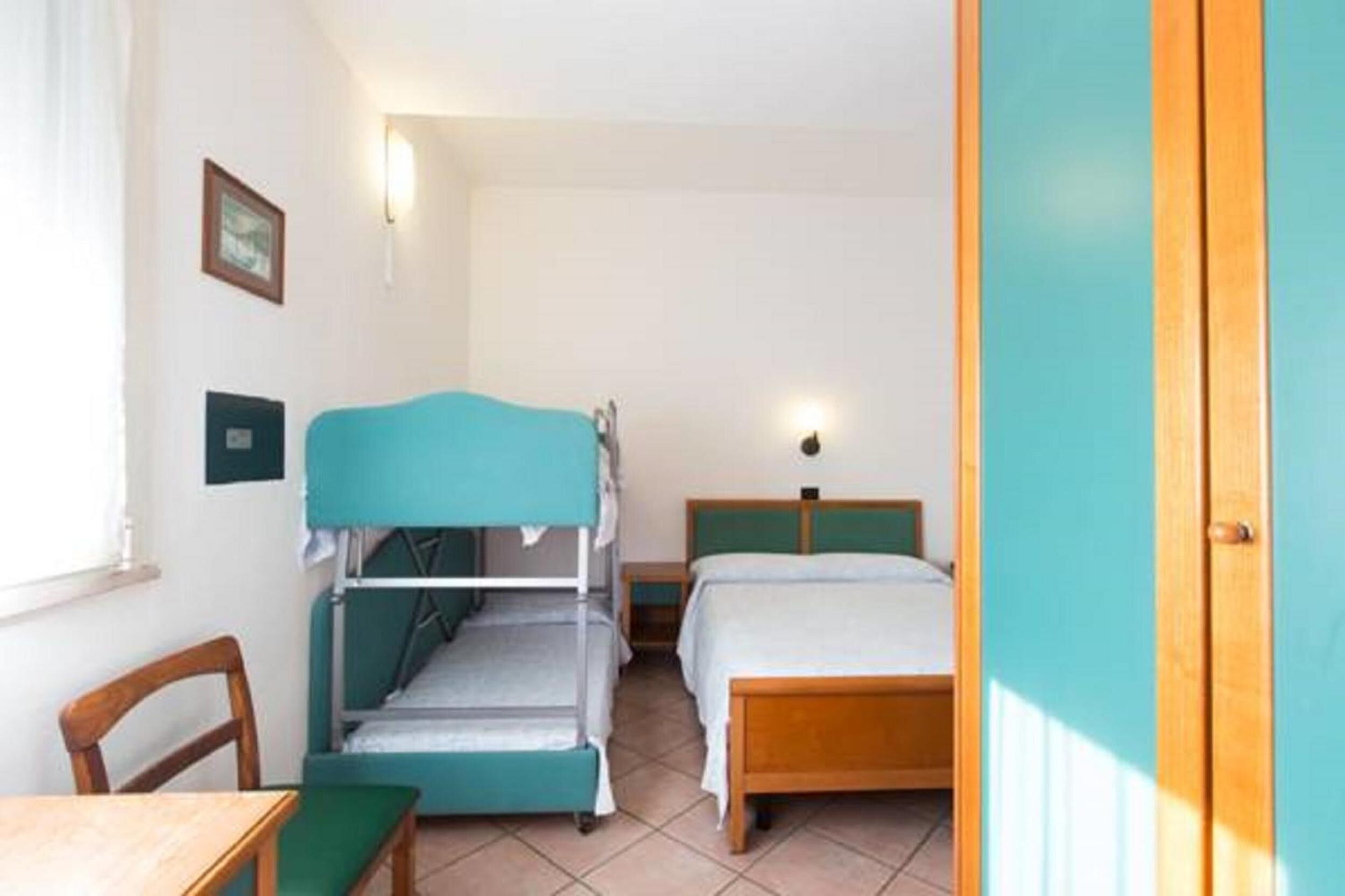 A room with bunk beds, a single bed, a desk, and a chair.