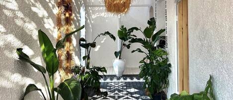 A hallway with a patterned floor, potted plants, and a hanging light fixture.