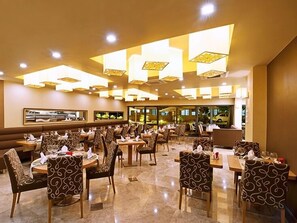 Un restaurante espacioso con techos altos, sillas estampadas y mesas dispuestas para comer.