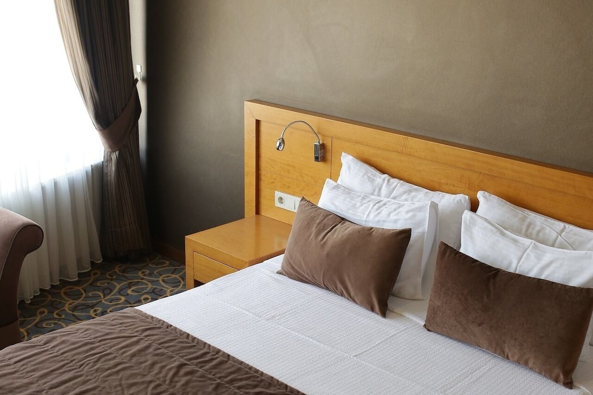 A hotel room with a large bed, wooden headboard, and a nightstand.