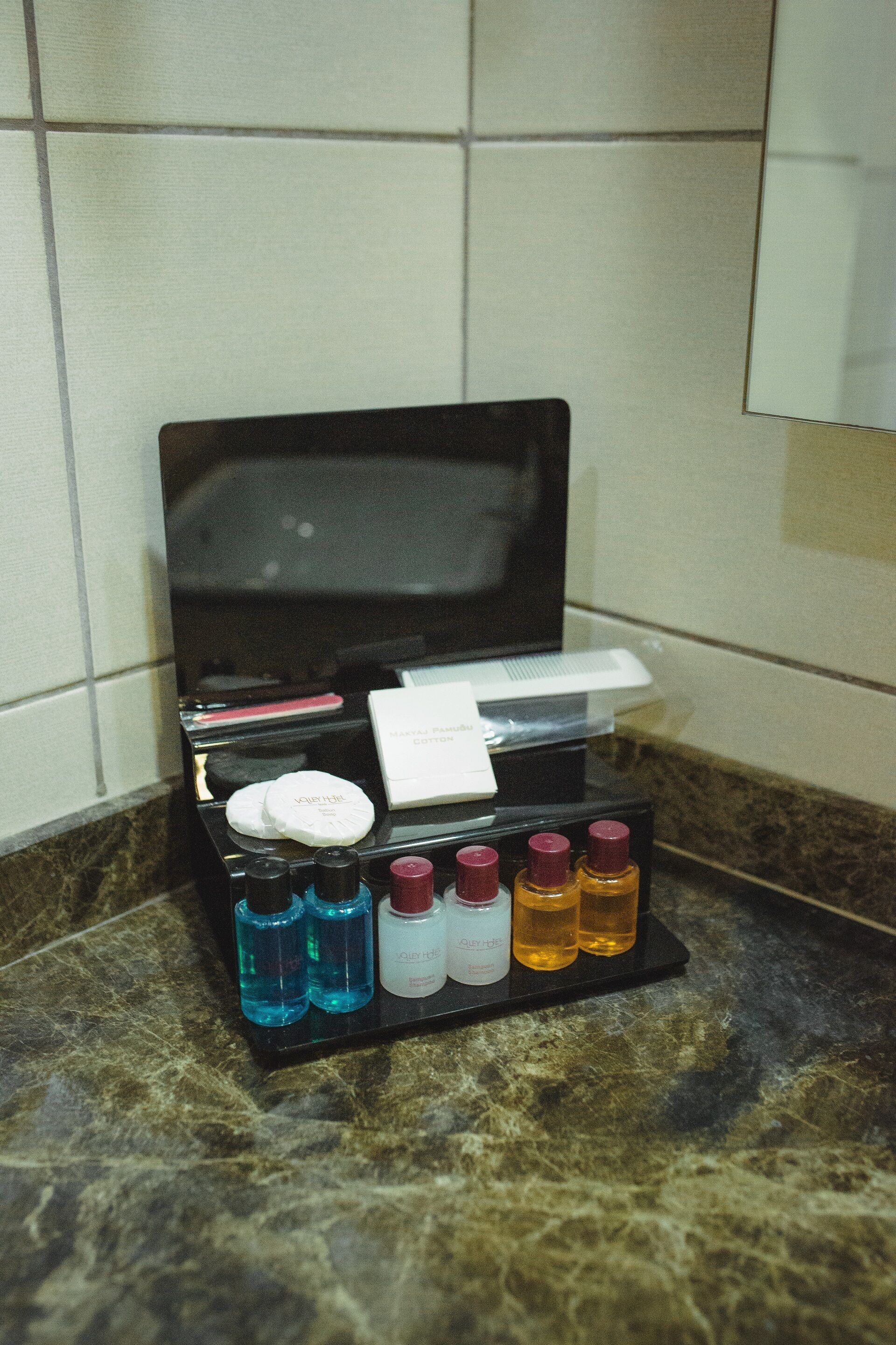 Un meuble-lavabo de salle de bain avec un plateau noir contenant divers articles de toilette.