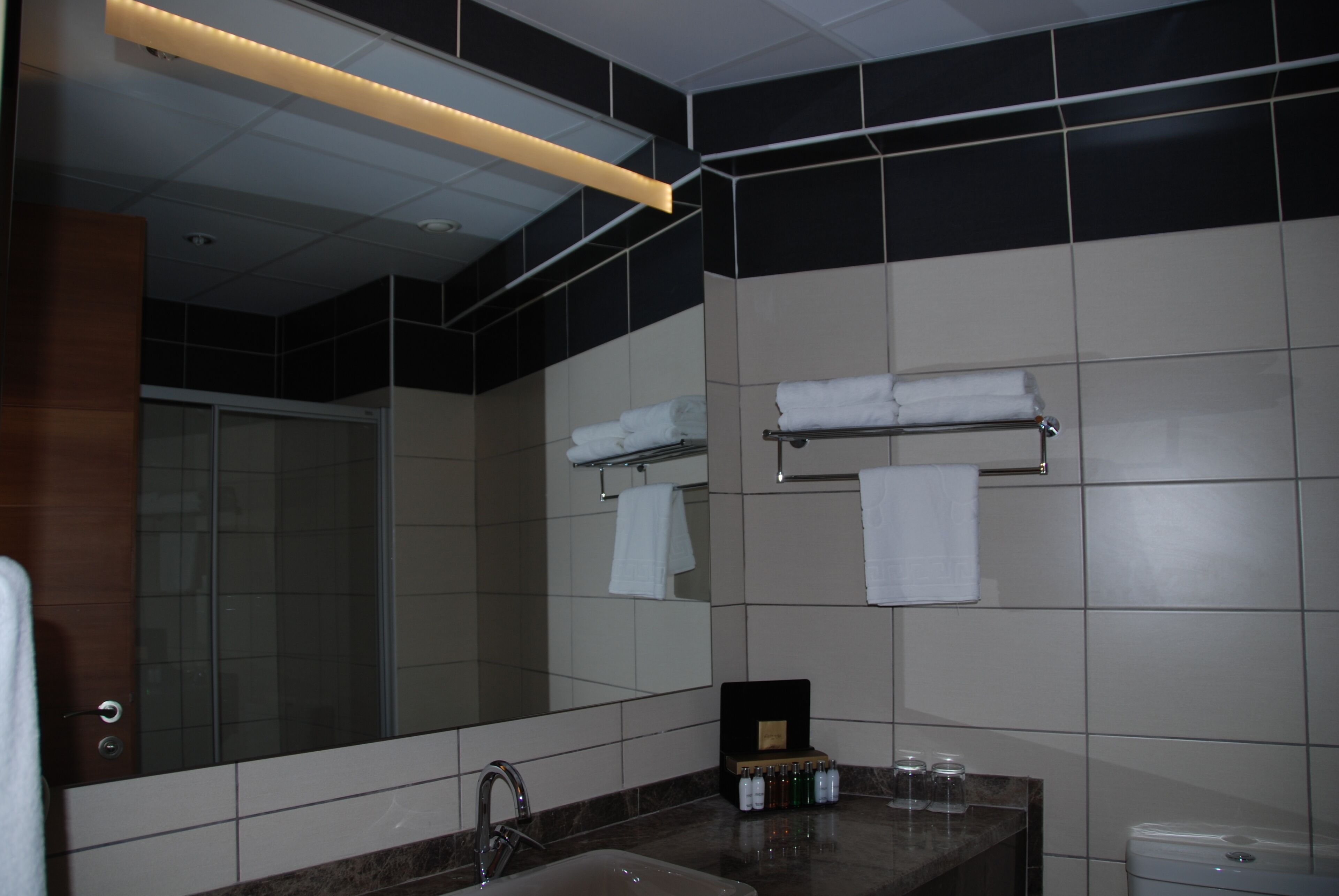 A modern bathroom with a large mirror, a sink, and a towel rack.