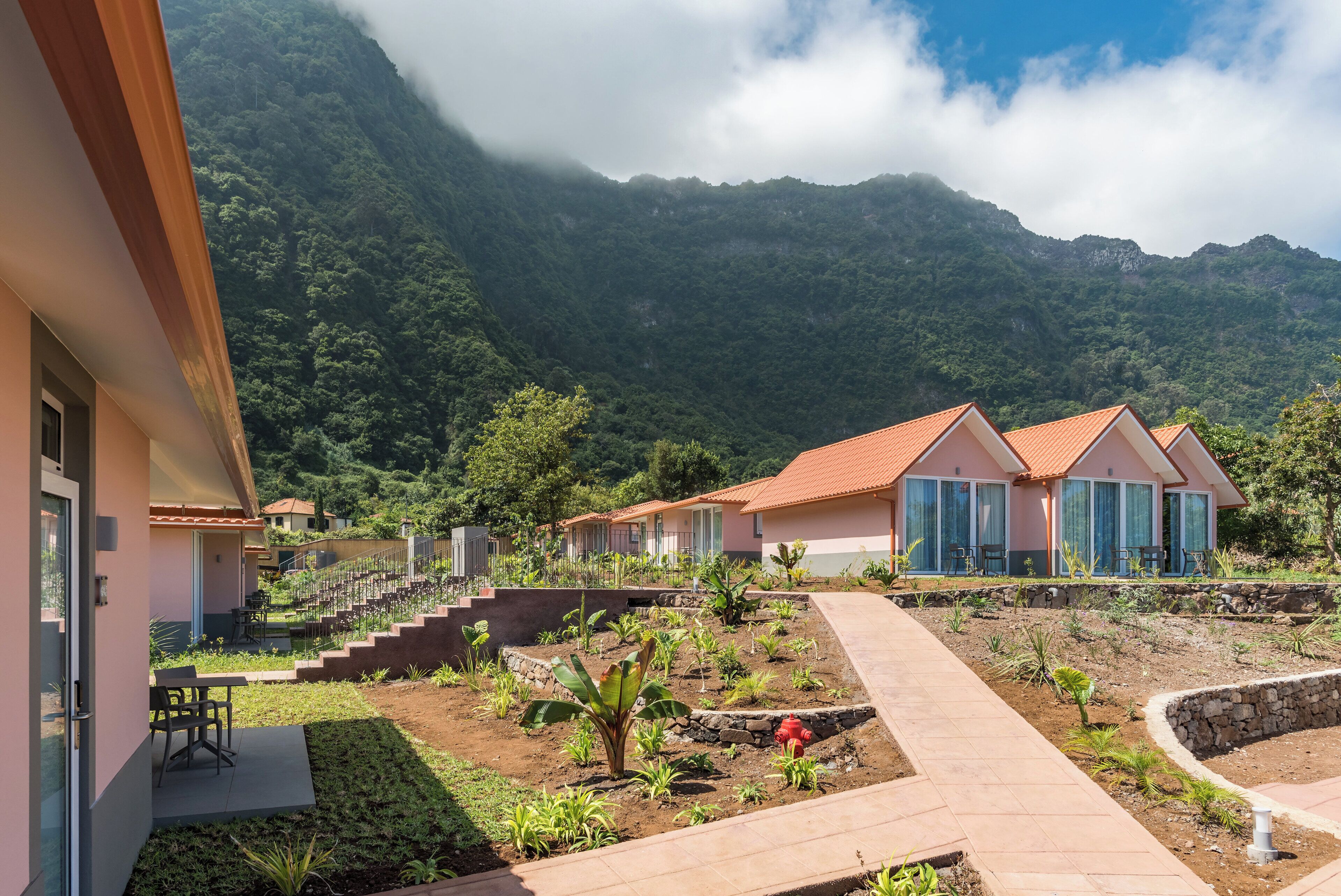 A resort with multiple buildings, a paved walkway, and a mountainous backdrop.